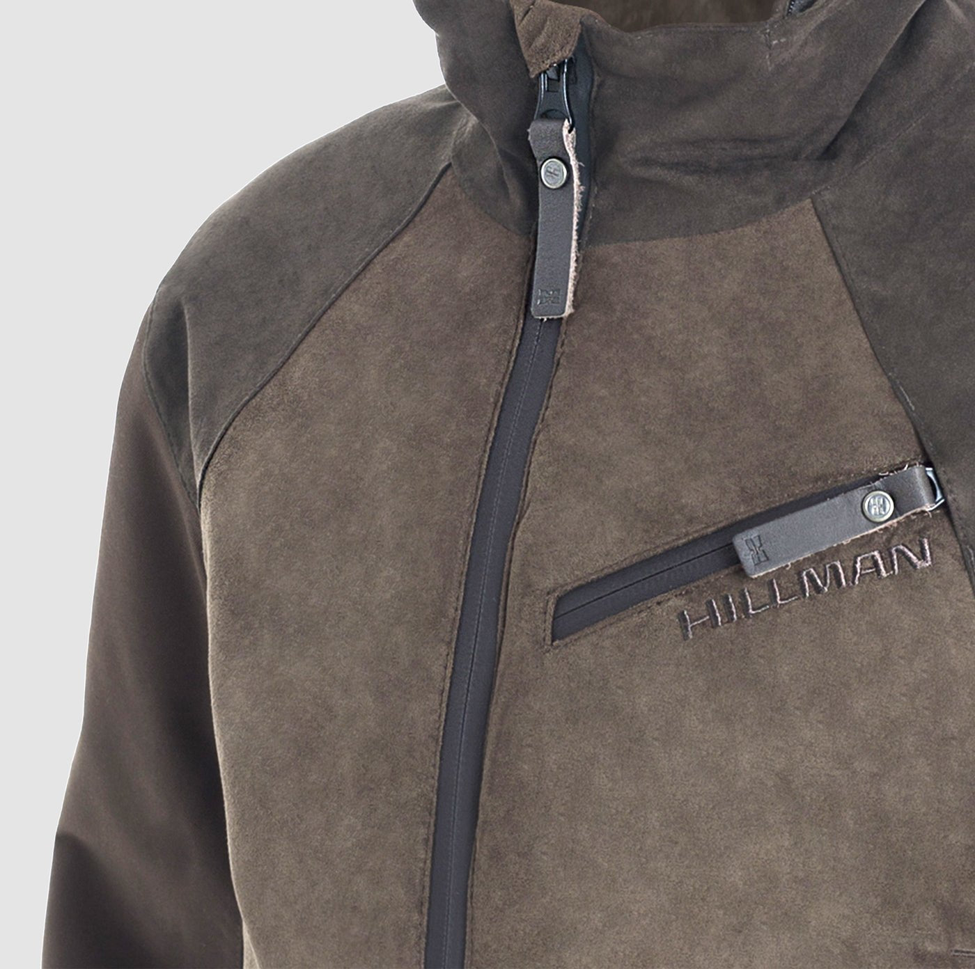 Nahaufnahme der Hillman Jagdjacke Herren Winter - Wasserdicht & Warm | Fusion™. Diese braune, wildlederartige Jacke hat einen Reißverschluss, eine Brusttasche mit "HILLMAN"-Stickerei und einen hohen Kragen.
