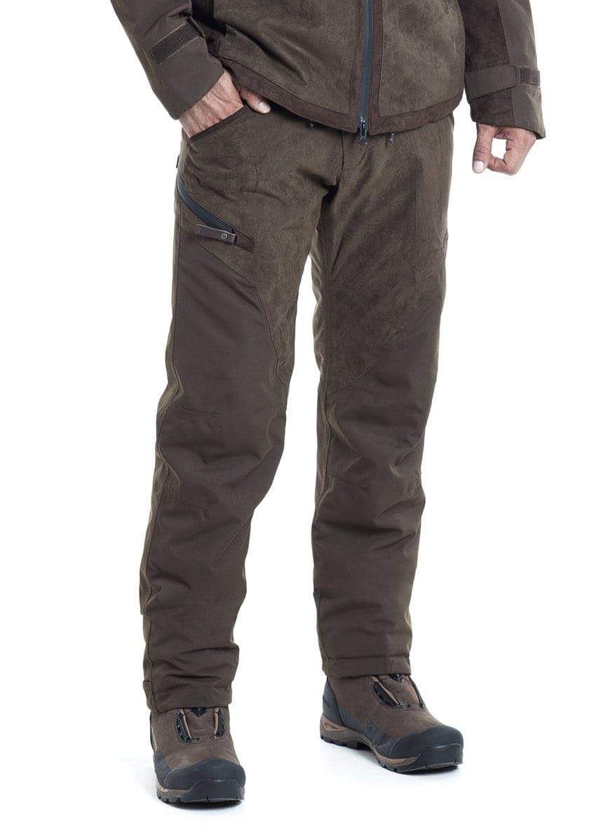 Eine Person steht da und trägt die Hillman Vorbestellung Jagdhose Fusion – Winterhose | OAK, eine passende braune Jacke und Wanderstiefel, von den Schultern abwärts vor einem weißen Hintergrund zu sehen – ideal für die Jagd bei jedem Wetter.