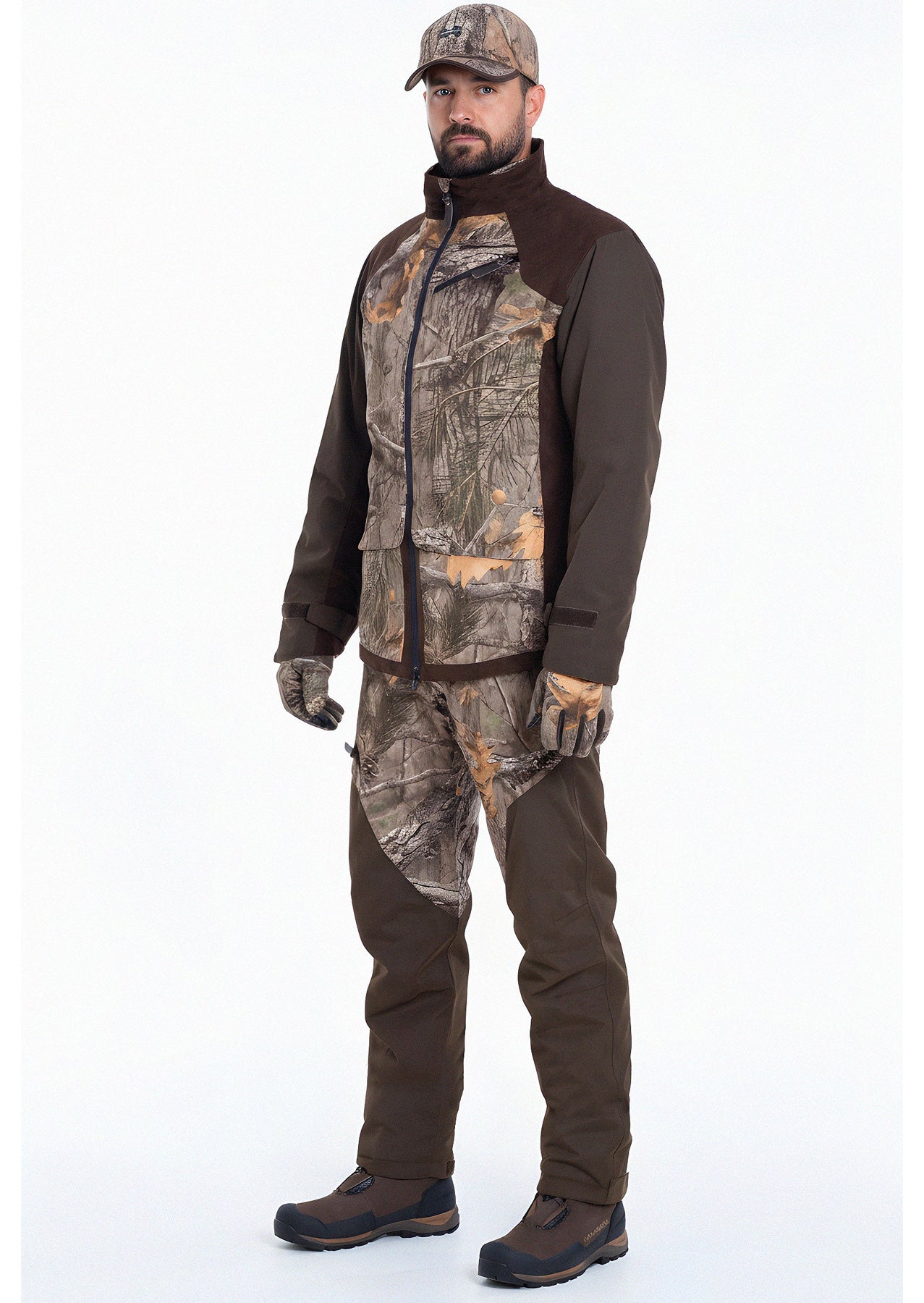 Ein Mann steht mit dem Gesicht nach vorne in der Fusion 3DX Tarnjacke Jagd von Hillman mit passender Hose, Hut, Handschuhen und braunen Stiefeln vor einem schlichten weißen Hintergrund.