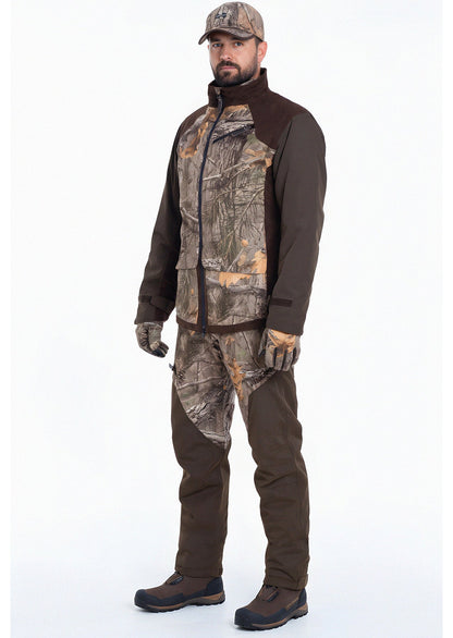Ein Mann steht mit dem Gesicht nach vorne in der Fusion 3DX Tarnjacke Jagd von Hillman mit passender Hose, Hut, Handschuhen und braunen Stiefeln vor einem schlichten weißen Hintergrund.