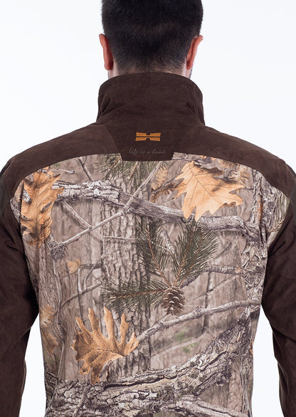 Ein Mann ist von hinten zu sehen, der die Hillman Tarnjacke Jagd | Jagdjacke Camouflage - Fusion 3DX mit braunem Kragen und Schultern trägt; die Rückseite zeigt eine Tarnung aus Baumzweigen, Tannennadeln und Herbstblättern.
