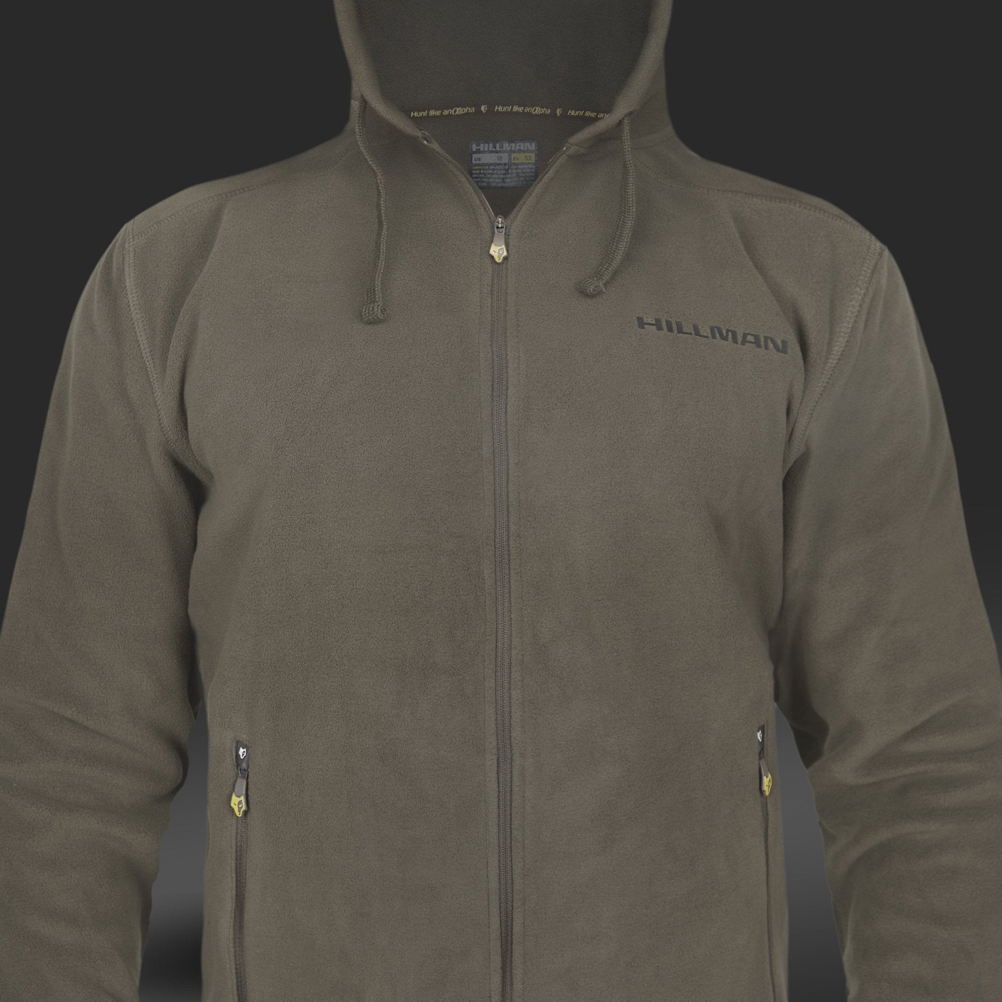 Der olivgrüne HOODIE-RUCKSACK mit Reißverschluss von Hillman® verfügt über eine Kapuze, lange Ärmel und den gestickten Schriftzug „HILLMAN“ auf der linken Brust. Diese vielseitige Jacke hat einen durchgehenden Frontreißverschluss und zwei Taschen, die jeweils durch gelbe Laschen auf schlichtem, dunklem Hintergrund hervorgehoben sind.